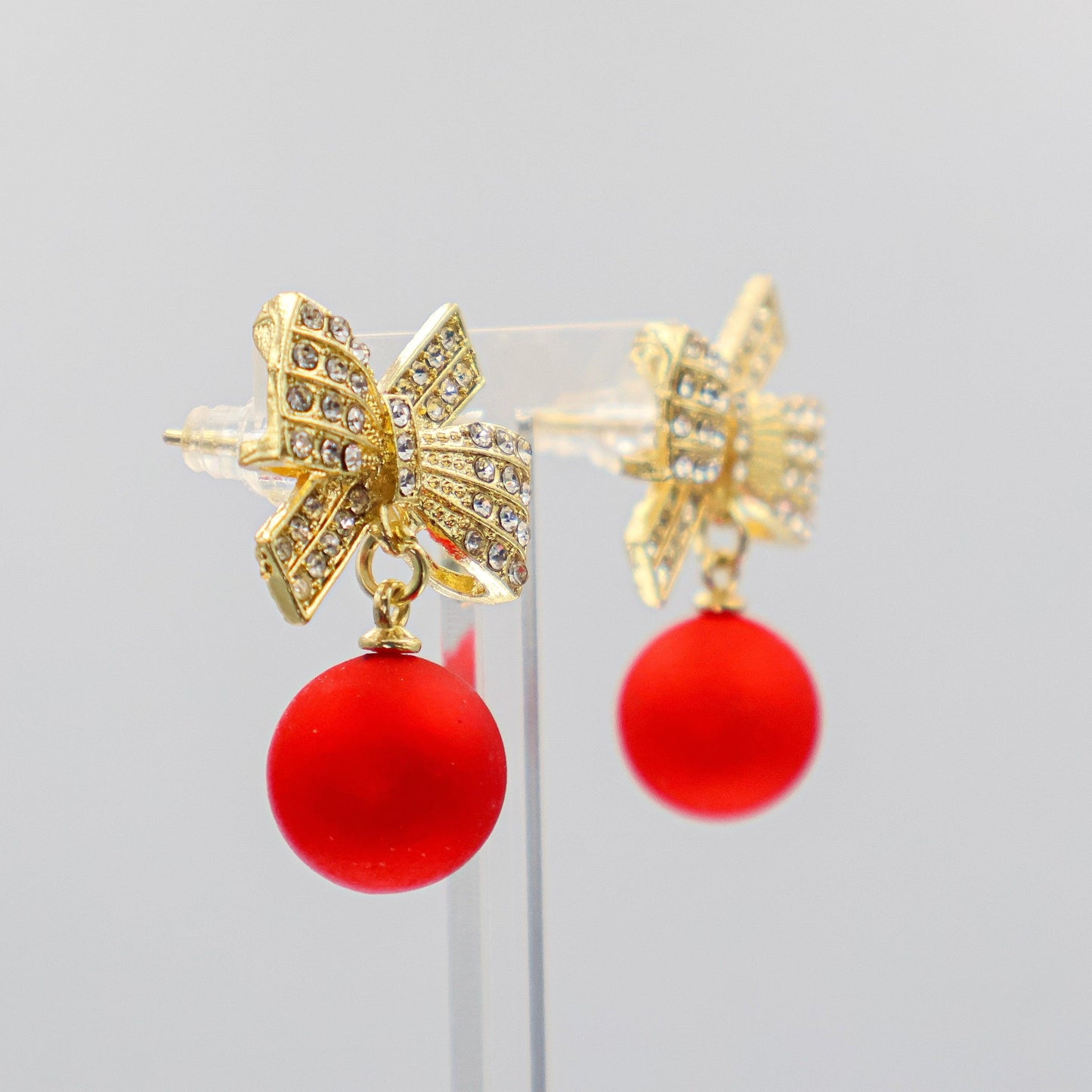 Sparkly gold bow drop earrings with red bauble charm – holiday party style